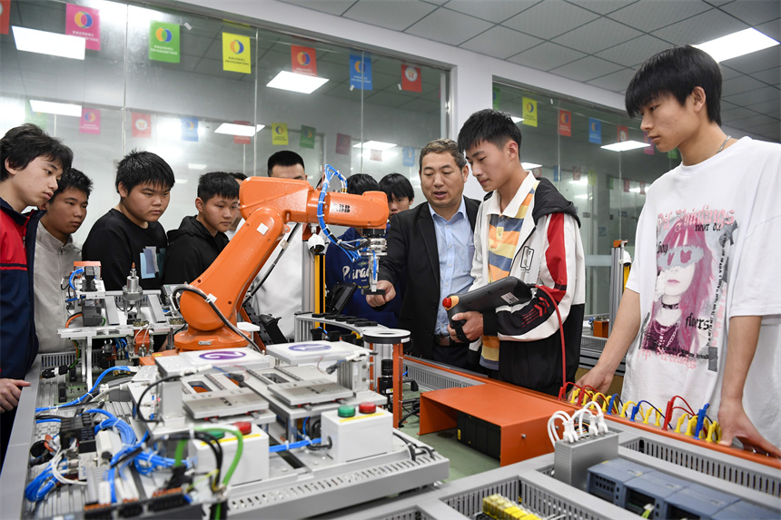 學(xué)生在老師的指導(dǎo)下進(jìn)行工業(yè)機(jī)器人的操作實訓(xùn)。周亮攝